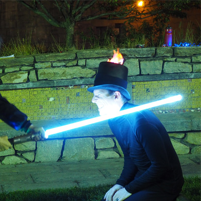 a SCUL pilot wearing a flaming top hat is being knighted with a lightsaber