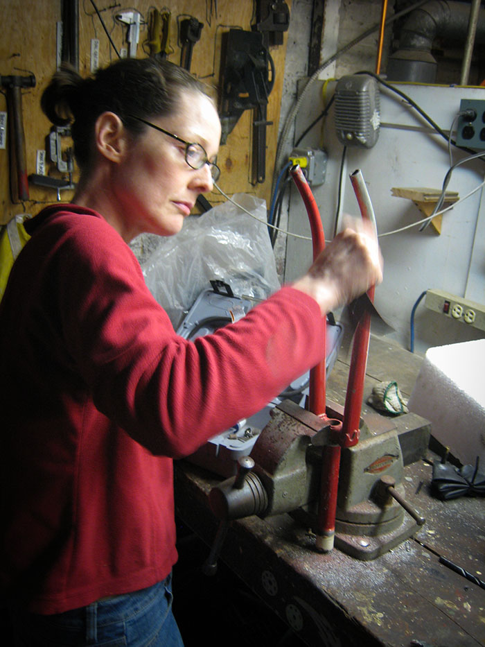 a woman sands the tips of a bicycle fork where the dropouts have been sawed off