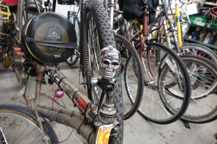 A plastic skull with red LED eyes mounted on the front of a heavily modified bicycle