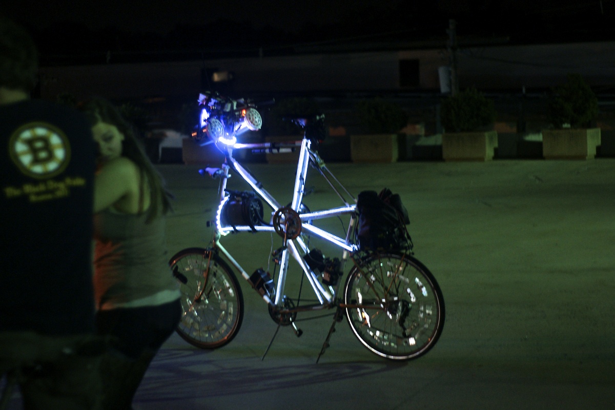 a tallbike adorned with LED strips is parked in an empty lot