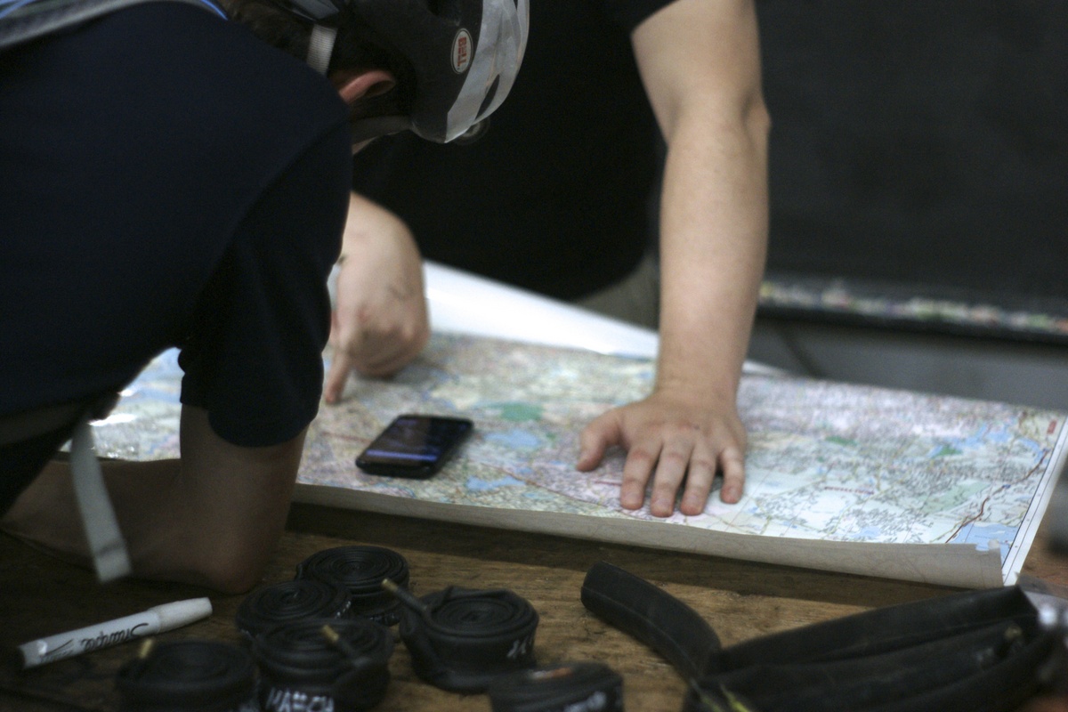 a closeup shot of people looking over a paper map layed out on a bench