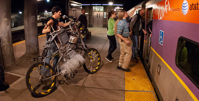A huge tallbike is being sized up to see it it will fit on the commuter rail