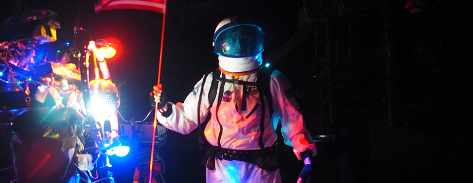 SCUL pilot in an astronaut suit holding a flag at night