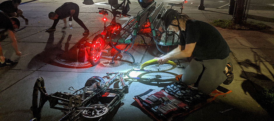 illustration of two happy people fixing a bicycle outside with a took roll on the ground.